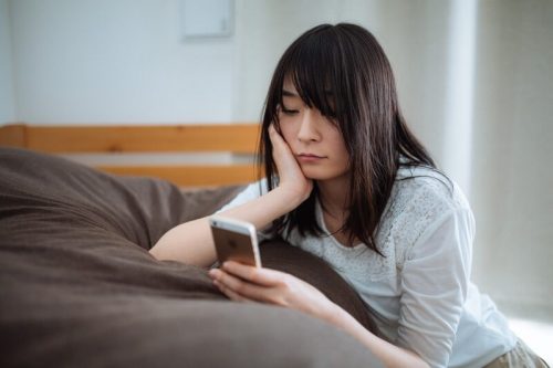 スマホを見て悩む女性